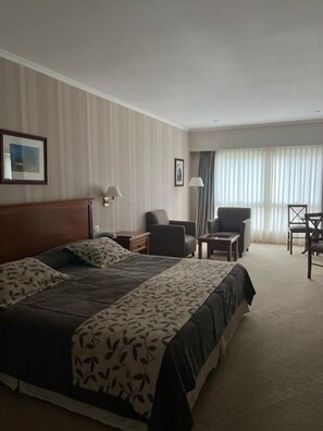 A hotel room with a large bed, a desk, a chair, and a window with curtains. - Howard Johnson by Wyndham Rio Ceballos (Río Ceballos)