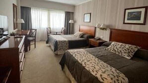 Une chambre d’hôtel avec deux lits, un bureau, une chaise et un téléviseur.