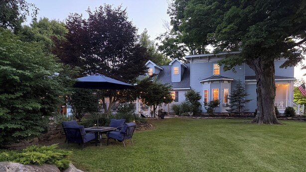 Il s’agit d’une propriété résidentielle dotée d’une pelouse bien entretenue, d’une terrasse avec mobilier d’extérieur et d’un grand arbre.