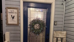 Une porte d’entrée bleu foncé ornée d’une guirlande, une plaque encadrée au-dessus, un paillasson et une enseigne décorative portant l’inscription « HOME » sur le porche.