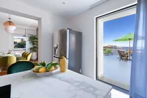 A modern kitchen with a marble countertop, a stainless steel refrigerator, and a dining area with yellow chairs and a green plant. - Nevada Infinity Villa | Pool, Terrace, View of Capri (Massa Lubrense)