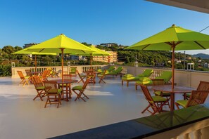 Eine Dachterrasse mit Sitzgelegenheiten im Freien, Sonnenschirmen und Blick auf die umliegende Landschaft.