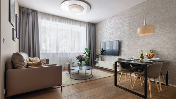 Ein modernes Wohnzimmer mit Sofa, Couchtisch, Esstisch und Fernseher.