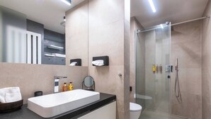 Ein modernes Badezimmer mit großem Waschbecken, Spiegel und Duschkabine aus Glas.