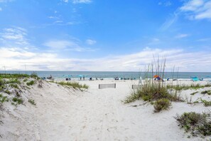Ein Strand mit Dünen, wolkenlosem Himmel und ruhiger See.