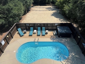 Ein Garten mit Swimmingpool, Liegestühlen und einer Holzterrasse.