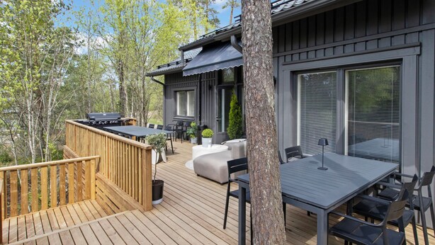 A deck with a table and chairs, a barbecue grill, and a sofa.