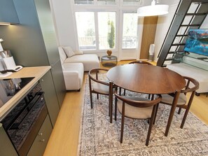 A modern kitchen with a dining area, a sofa, and a staircase with a TV.