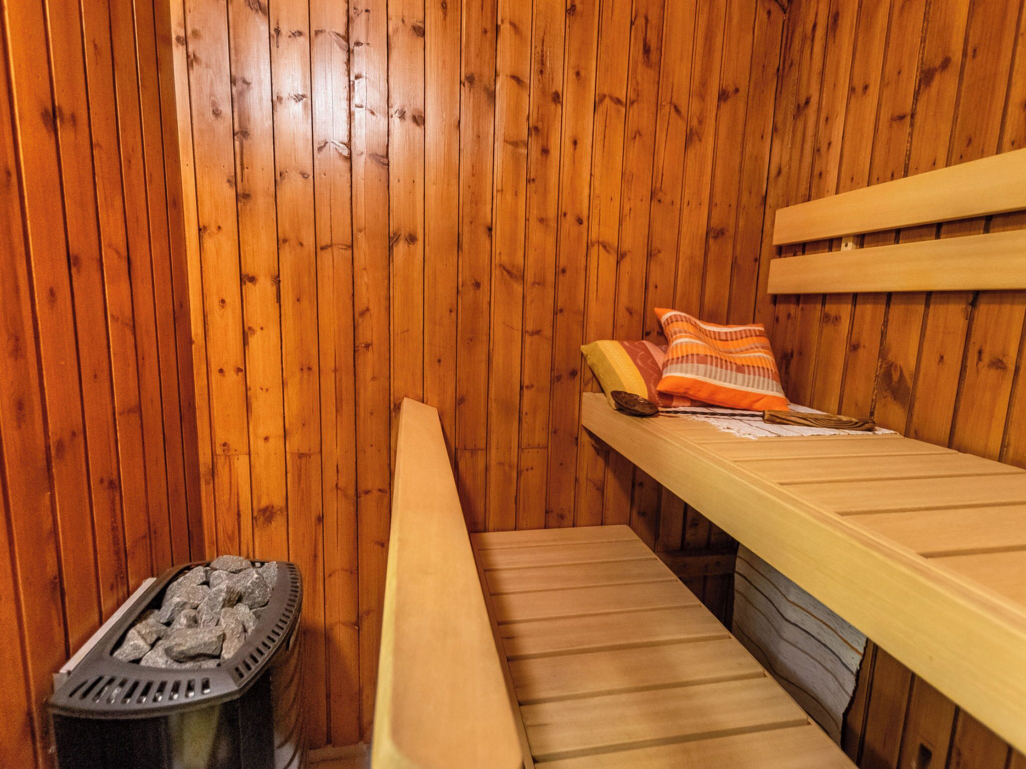 Una sauna amb parets de fusta, seients i un escalfador de pedra.