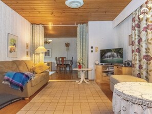 Una sala de estar con sofá, televisión, mesa y comedor con sillas.
