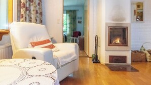 Ein Wohnzimmer mit Kamin, einem weißen Sessel und einer gemusterten Tischdecke.