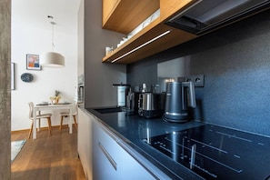 A modern kitchen with a black countertop, built-in appliances, and a dining area with a table and chairs. - Stylish Apartment in Prague's Historic Centre (Prague 1)