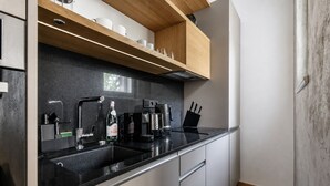 A modern kitchen with a black countertop, stainless steel appliances, and wooden shelves above the sink. - Stylish Apartment in Prague's Historic Centre (Prague 1)