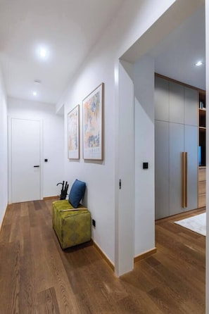 A hallway with wooden flooring, a green patterned bench, and a door. - Stylish Apartment in Prague's Historic Centre (Prague 1)