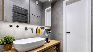 A modern bathroom with a large white sink, wooden vanity, and a mirror. - Stylish Apartment in Prague's Historic Centre (Prague 1)
