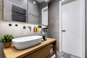 A modern bathroom with a large white sink, wooden vanity, and a mirror. - Stylish Apartment in Prague's Historic Centre (Prague 1)