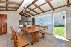 Ein Essbereich mit Holztisch und Bänken, im Hintergrund eine Küche und ein Wandgemälde eines Löwen.