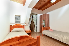 Ein Schlafzimmer mit zwei hölzernen Betten, einem Fenster mit Jalousien, einem Kleiderschrank und einem Deckenventilator.
