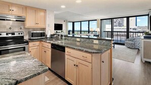 Una cocina moderna con encimeras de granito, electrodomésticos de acero inoxidable y armarios de madera.