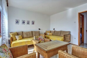 Ein Wohnzimmer mit einer Couch, zwei Sesseln, einem Couchtisch und einem gemusterten Teppich.
