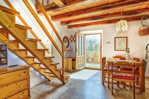 Eine Holztreppe führt zu einem Balkon mit Essbereich und Blick auf Bäume.