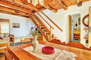 Ein Holzesstisch mit einer Vase und einer roten Schüssel, eine Holztreppe und ein Bild an der Wand.