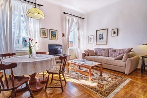 Ein Wohnzimmer mit rundem Tisch, Sofa und Fernseher.