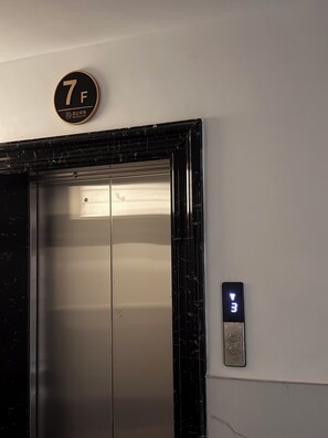 Ein Aufzug mit digitaler Anzeige, einem an der Wand befestigten Schild mit der Etage 7 und einem Rauchverbotsschild.