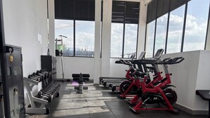 Ett gym med träningsutrustning, stora fönster och ett klinkergolv.