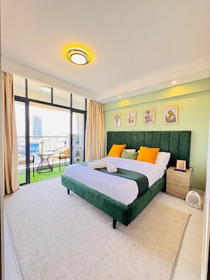 Ein Hotelzimmer mit einem großen Bett, Blick auf die Stadt und einem Balkon mit Gartenmöbeln.