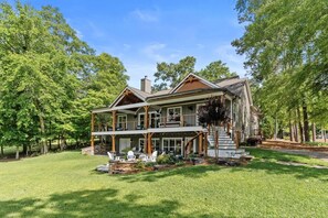 A two-story house with a porch, a stone foundation, and a well-maintained lawn.