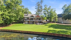 Une maison à deux étages avec une grande pelouse devant et une piscine.