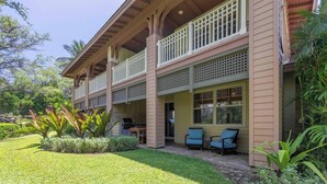 Un edificio de dos pisos con balcón, mesas al aire libre y zona de barbacoa.