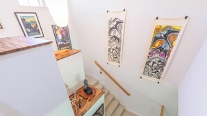 Una escalera con obras de arte en las paredes, una mesa de madera con una escultura y un cuadro enmarcado.