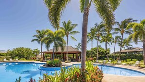 Una piscina rodeada de palmeras y sillas de descanso.