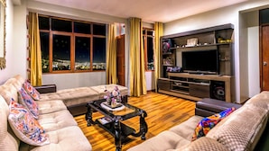 A living room with a sofa set, a coffee table, a TV stand, and a window with curtains. - 5 min to the center! | Beautiful and homely | Incredible views & private parking (Cusco)