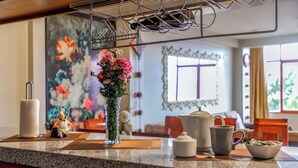 A kitchen counter with a vase of flowers, a coffee maker, a teapot, a mug, and a bowl. - 5 min to the center! | Beautiful and homely | Incredible views & private parking (Cusco)
