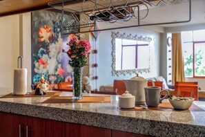Eine Küchenarbeitsplatte mit Blumen in einer Vase, einer Kaffeemaschine, einem Teekessel, einer Tasse und einer Schüssel.