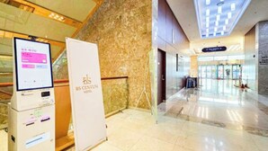 A hotel reception area with a digital check-in kiosk, a reception desk, and a marble wall. - BS centum hotel (Busan)