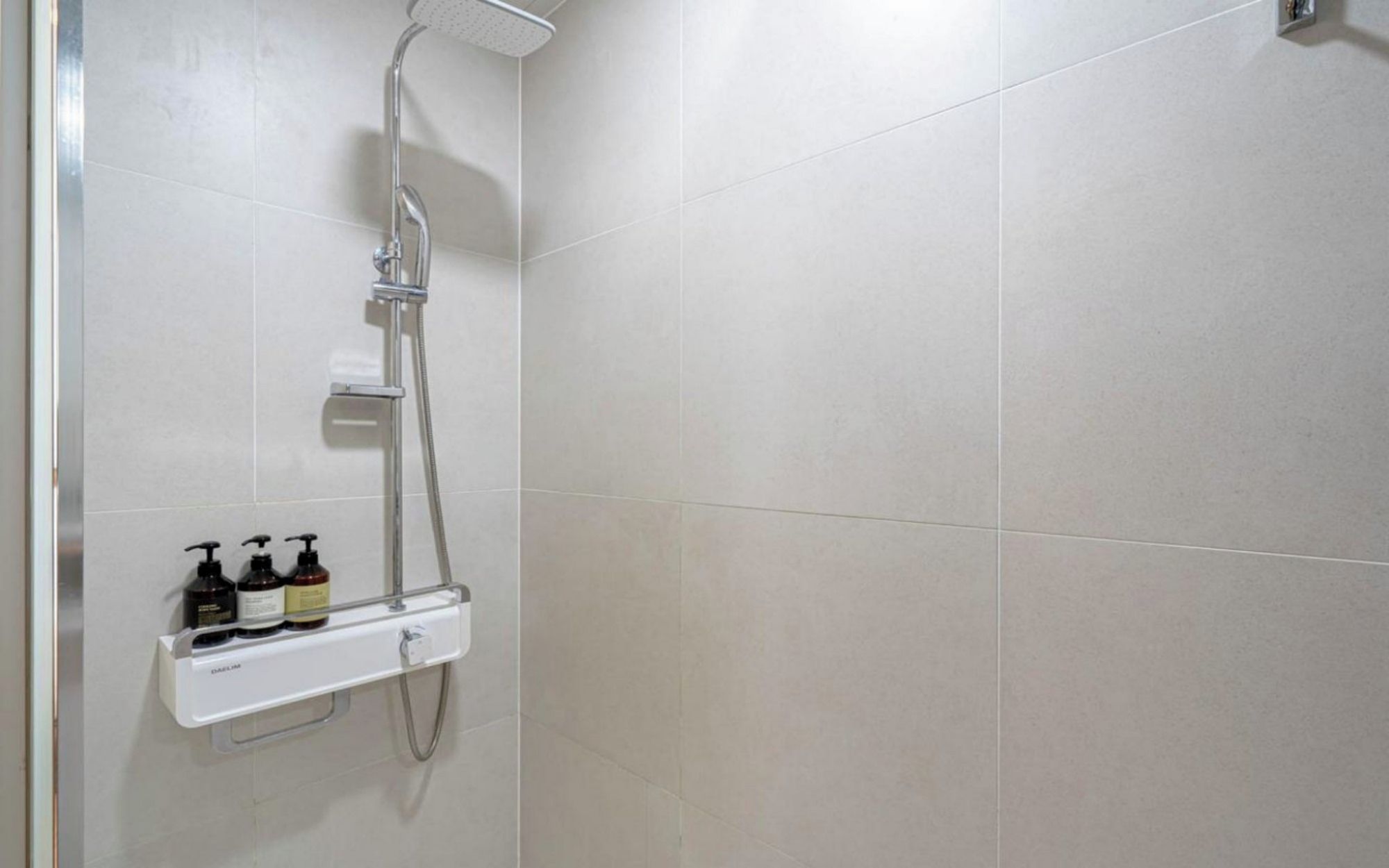 A shower with a handheld showerhead and a wall-mounted control panel.