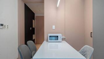 A conference room with a long table, two chairs, a microwave, and a door leading to another room.