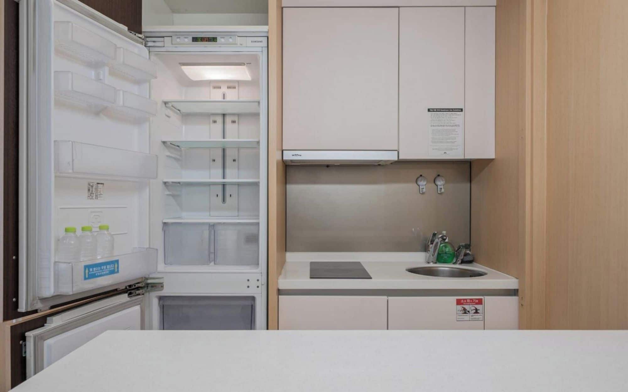 A compact kitchenette with a built-in refrigerator, a sink, and a small countertop.