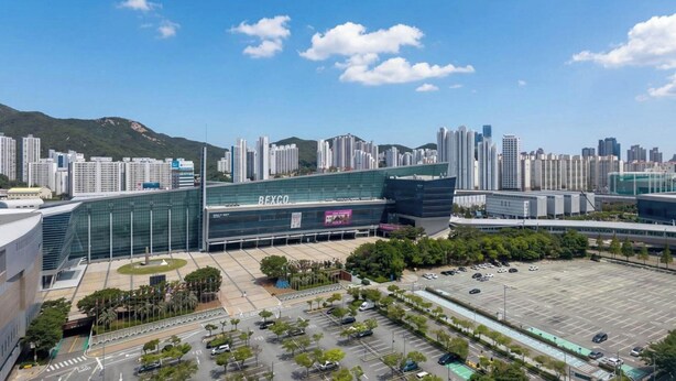 A modern building with a large glass facade, surrounded by a parking lot and other high-rise buildings. - BS centum hotel (Busan)