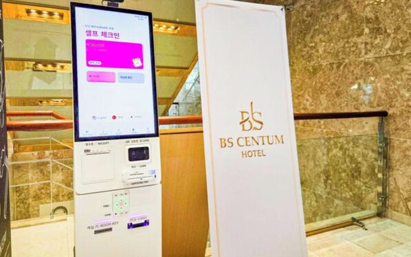 A digital check-in kiosk and a sign for the BS Centum Hotel.