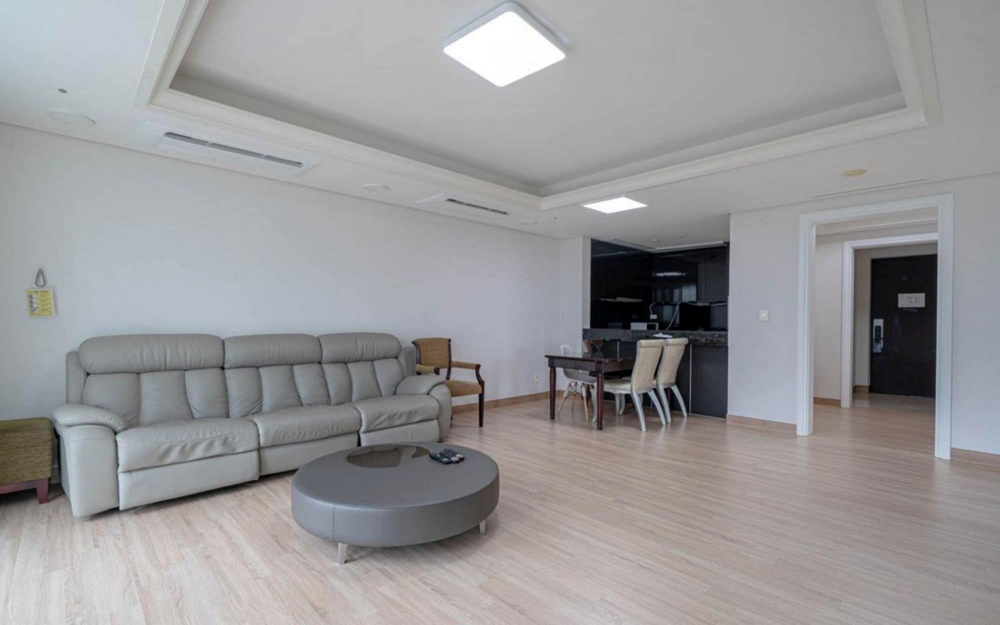 A modern living room with a sofa, a round coffee table, and a dining area with chairs.