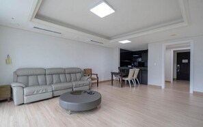 Una sala de estar moderna con un sofá, una mesa redonda de centro y un comedor con sillas.