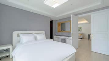 A modern hotel room with a large bed, a desk, a mirror, and a wardrobe.