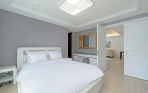 Una habitación de hotel moderna con una cama grande, un escritorio, un espejo y un armario.