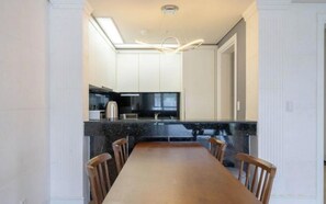 A modern kitchen with a long dining table and chairs, a built-in oven, and a large window. - BS centum hotel (Busan)