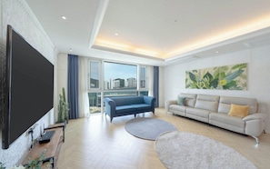 A modern living room with a large flat-screen TV, two sofas, a coffee table, and a large window with a city view. - BS centum hotel (Busan)